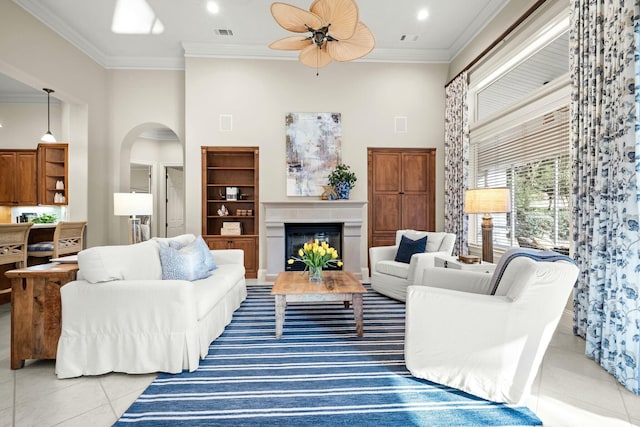 living room featuring light tile patterned floors, visible vents, arched walkways, a towering ceiling, and ornamental molding