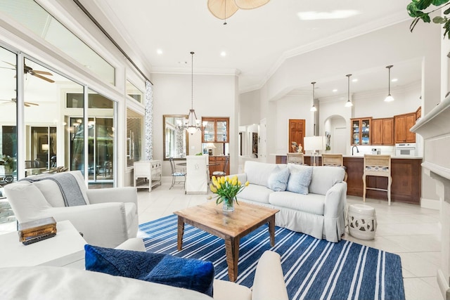 living area with arched walkways, crown molding, light tile patterned floors, recessed lighting, and ceiling fan with notable chandelier