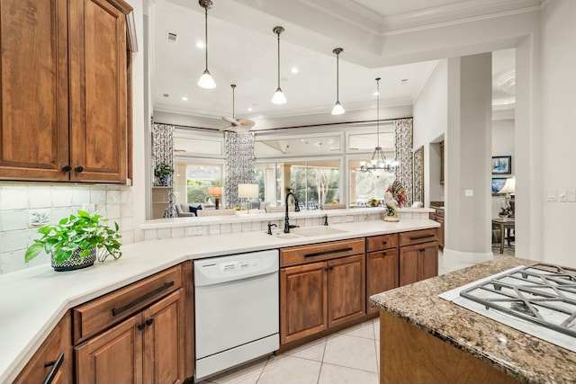 kitchen with white appliances, light tile patterned floors, brown cabinetry, crown molding, and a sink