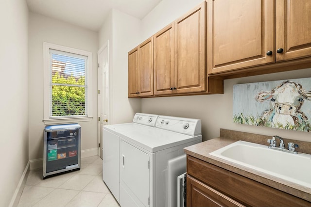 laundry room featuring cabinet space, light tile patterned floors, baseboards, washing machine and clothes dryer, and a sink