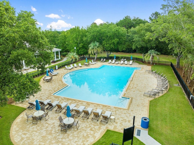 community pool with fence, a patio, and a yard