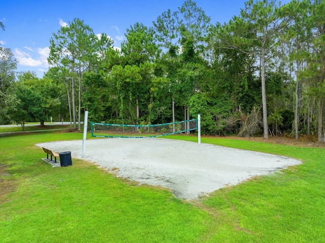 view of community with driveway, volleyball court, and a yard