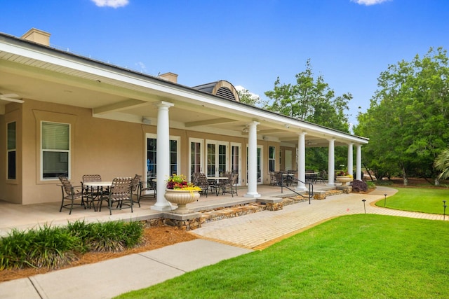 exterior space with a patio area, a lawn, and stucco siding