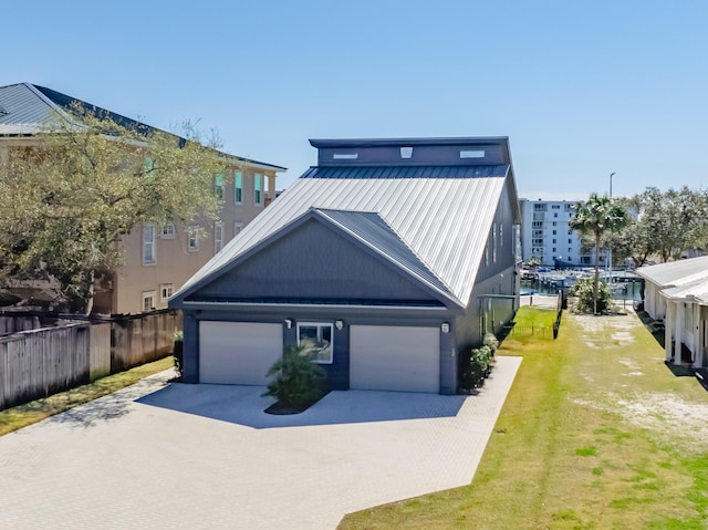 view of front of home with metal roof, a garage, fence, concrete driveway, and a front lawn