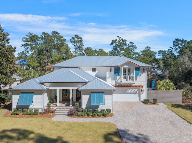 view of front of home featuring a balcony, metal roof, decorative driveway, and a front yard