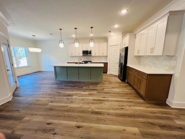 kitchen featuring appliances with stainless steel finishes, decorative backsplash, a sink, and wood finished floors