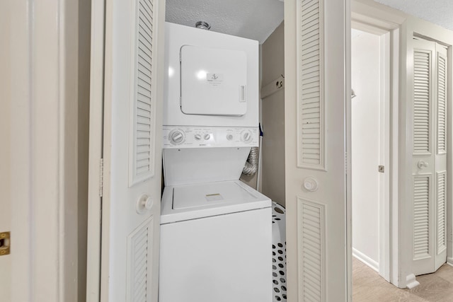 laundry room featuring stacked washer and clothes dryer, a textured ceiling, and laundry area