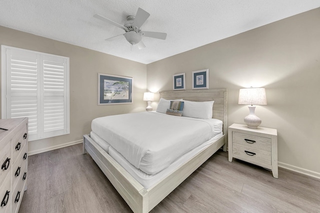 bedroom featuring baseboards, ceiling fan, light wood-style flooring, and a textured ceiling