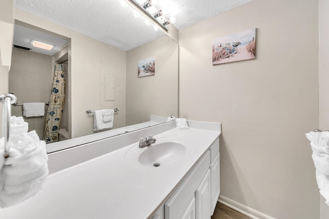 full bathroom featuring baseboards, wood finished floors, a textured ceiling, and vanity