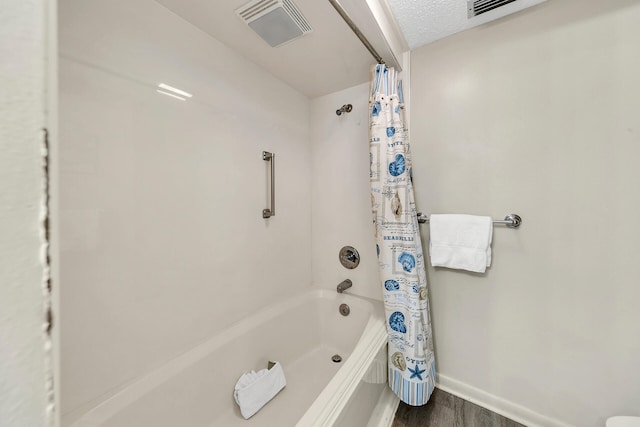 full bathroom with a textured ceiling, wood finished floors, visible vents, baseboards, and shower / bath combo