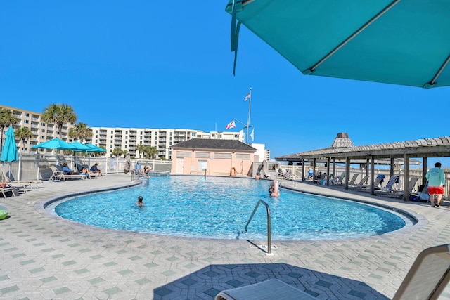 community pool with a patio area and fence