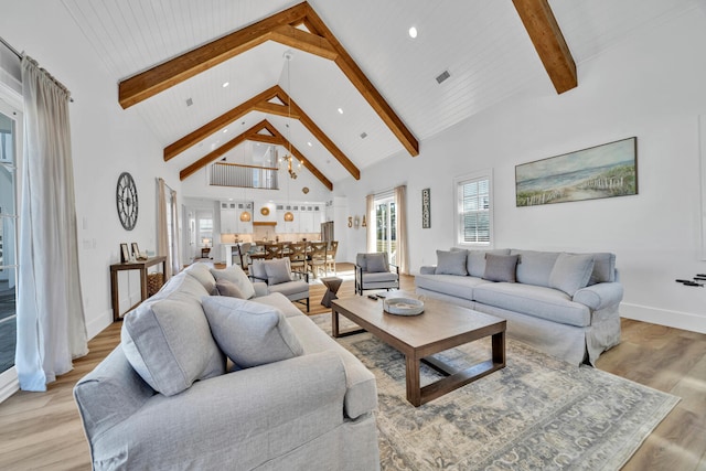 living area featuring beam ceiling, light wood-style floors, baseboards, and high vaulted ceiling