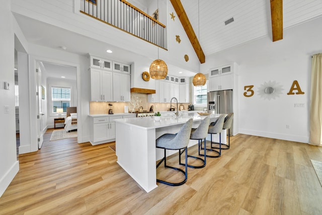 kitchen featuring light countertops, light wood-style flooring, tasteful backsplash, and high vaulted ceiling