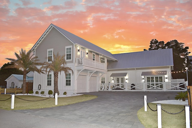 view of front of property with a garage, decorative driveway, a balcony, and a lawn