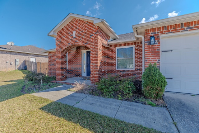 view of front facade with a front yard, brick siding, fence, and an attached garage