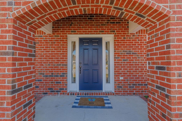 doorway to property featuring brick siding