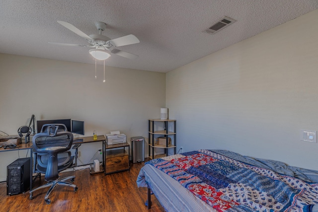 bedroom featuring a ceiling fan, a textured ceiling, visible vents, and wood finished floors