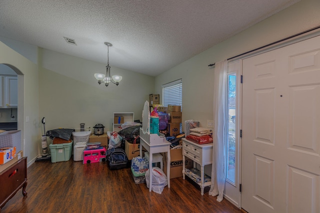 entryway with visible vents, arched walkways, wood finished floors, an inviting chandelier, and vaulted ceiling