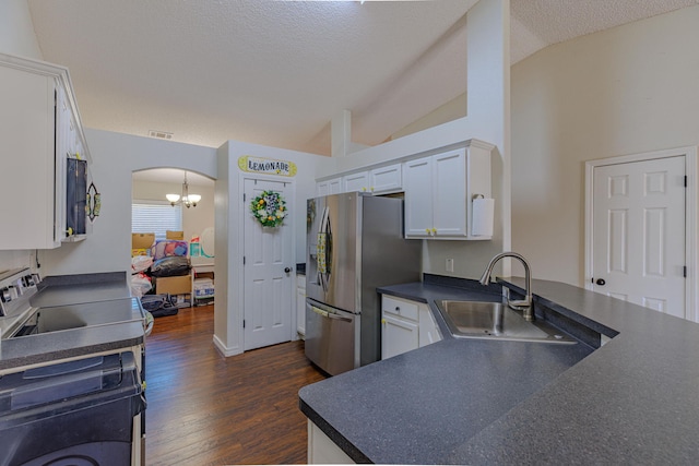 kitchen with arched walkways, lofted ceiling, a sink, appliances with stainless steel finishes, and dark countertops