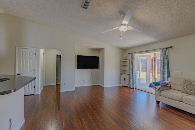 living area with dark wood-style floors, arched walkways, lofted ceiling, visible vents, and a ceiling fan