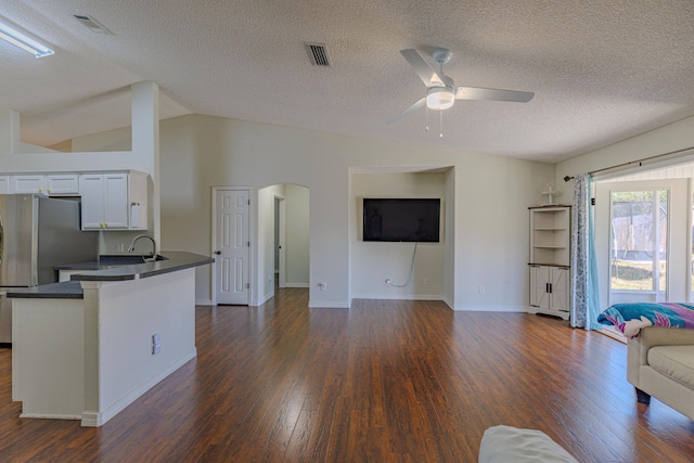 living area featuring arched walkways, lofted ceiling, dark wood-style flooring, visible vents, and a ceiling fan