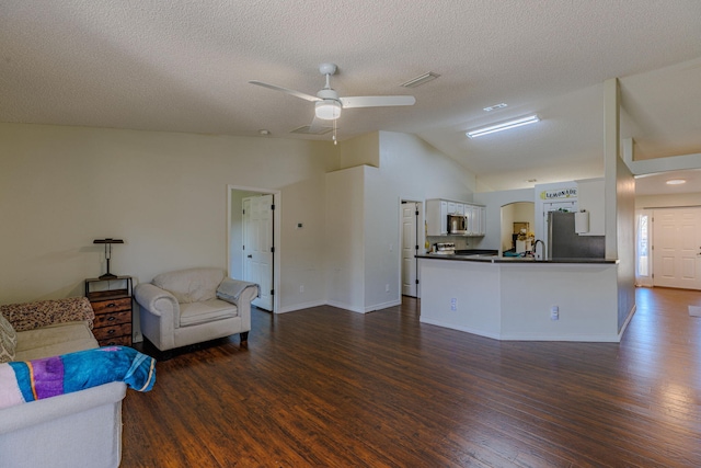 living area with dark wood-style floors, lofted ceiling, visible vents, and ceiling fan