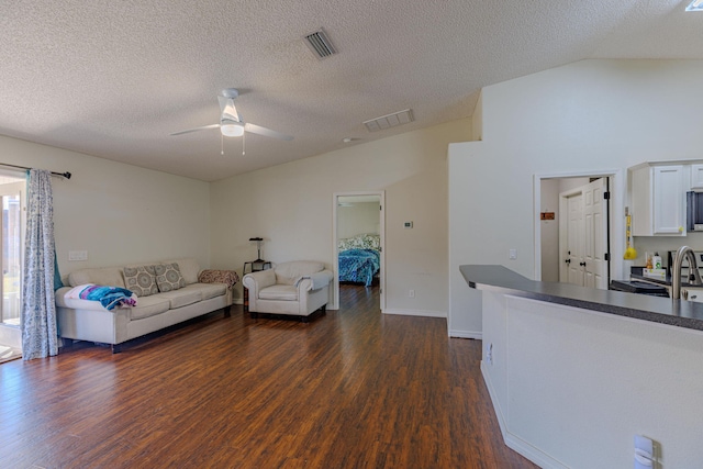 unfurnished living room featuring lofted ceiling, ceiling fan, dark wood-style floors, and visible vents