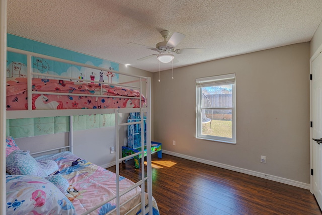 bedroom featuring ceiling fan, a textured ceiling, baseboards, and wood finished floors