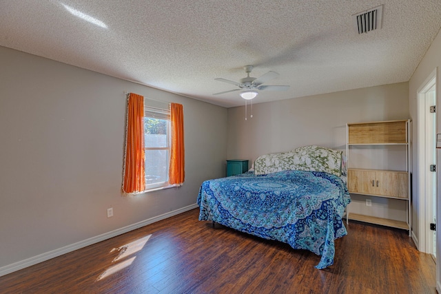 bedroom featuring ceiling fan, a textured ceiling, wood finished floors, visible vents, and baseboards