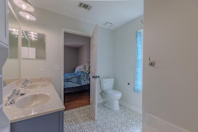 bathroom featuring toilet, visible vents, a sink, and ensuite bathroom