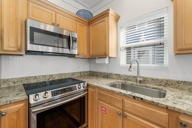 kitchen with appliances with stainless steel finishes, a sink, and light stone countertops