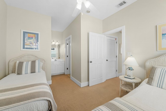 carpeted bedroom featuring a ceiling fan, visible vents, baseboards, and ensuite bathroom