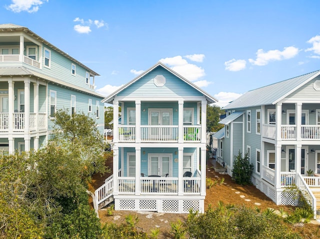 rear view of property with a balcony, covered porch, and french doors