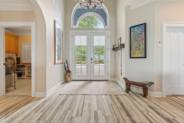 doorway to outside with french doors, a notable chandelier, light wood-style floors, ornamental molding, and baseboards