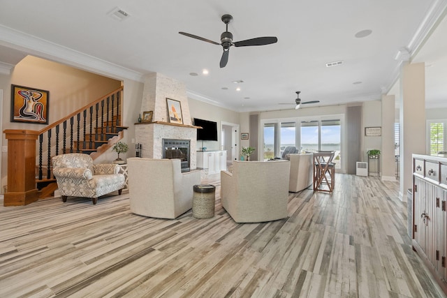 living area with a large fireplace, plenty of natural light, visible vents, and wood finished floors