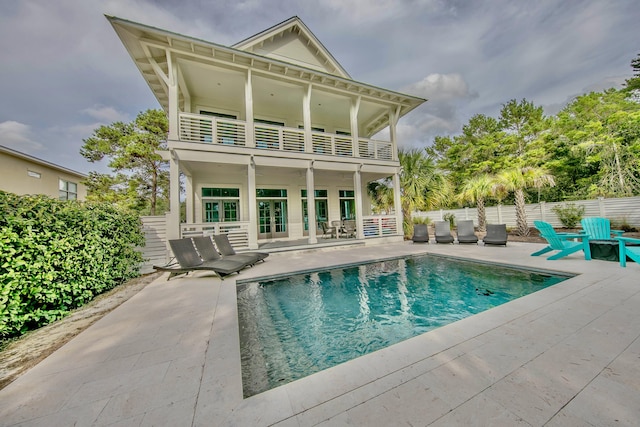 rear view of property featuring a fenced in pool, a patio, a balcony, and fence