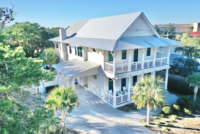 view of front of property featuring a chimney, driveway, metal roof, and a porch