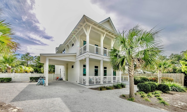 view of front facade with a balcony, covered porch, fence, driveway, and a carport