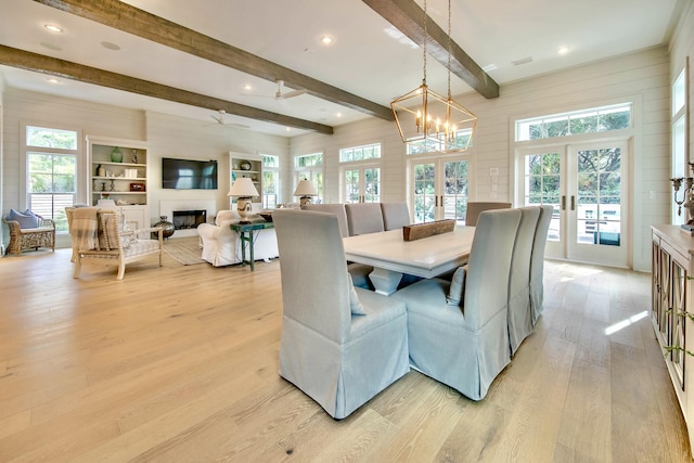 dining room with light wood-type flooring, a healthy amount of sunlight, a fireplace, and french doors