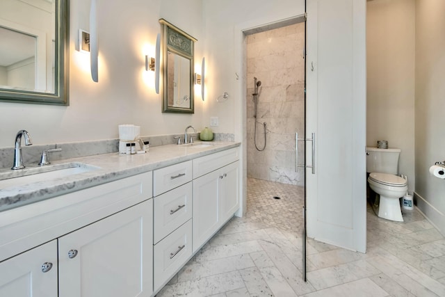 bathroom with double vanity, tiled shower, a sink, and toilet