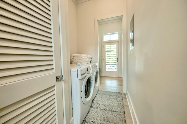 washroom with laundry area, light wood finished floors, independent washer and dryer, and baseboards