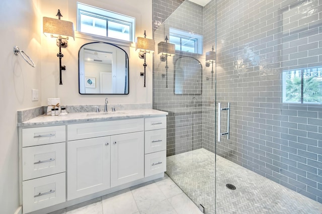 full bathroom featuring marble finish floor, tiled shower, and vanity