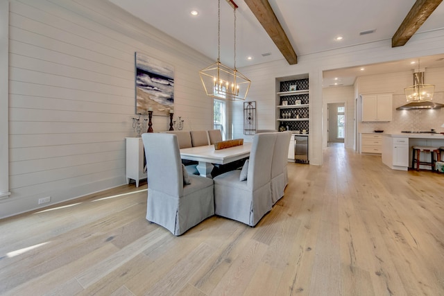 dining room with light wood finished floors, beam ceiling, and an inviting chandelier