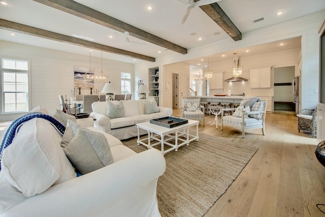 living room with recessed lighting, ceiling fan with notable chandelier, visible vents, light wood finished floors, and beamed ceiling