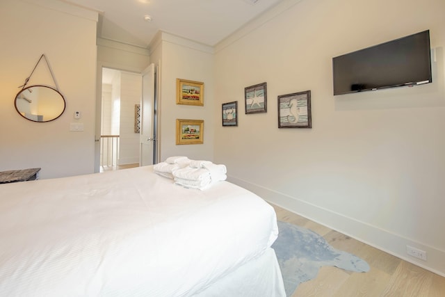 bedroom with crown molding, baseboards, and wood finished floors