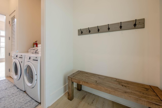 laundry room with laundry area, washing machine and dryer, and light wood-style floors