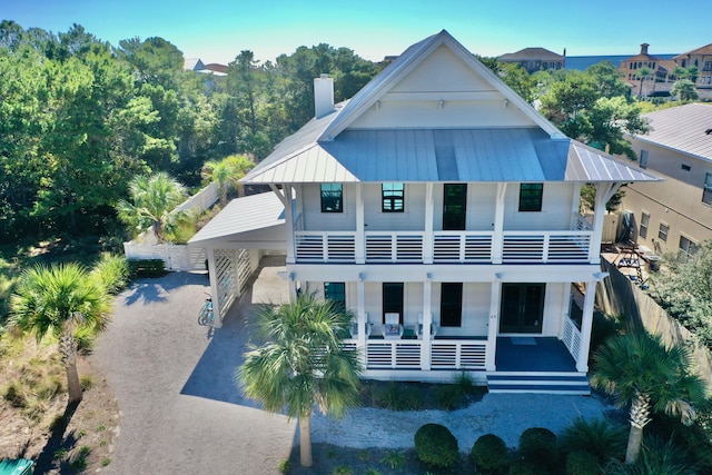 view of front of home featuring a chimney, metal roof, and a balcony