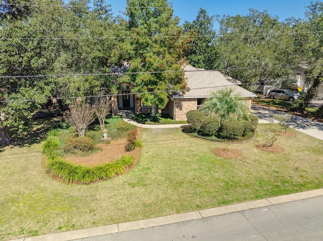 obstructed view of property featuring brick siding, a front lawn, and roof with shingles