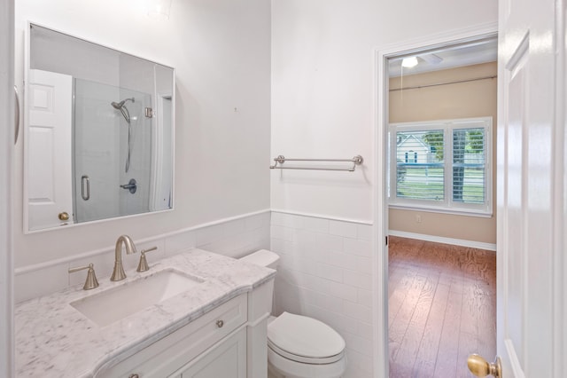 full bathroom with vanity, wood finished floors, a stall shower, tile walls, and toilet