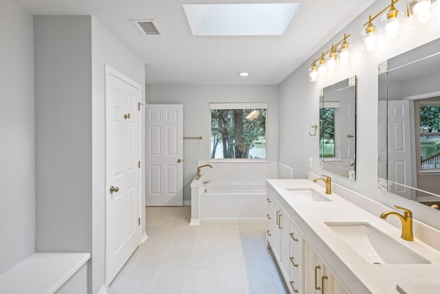 bathroom featuring a sink, visible vents, a garden tub, and a skylight